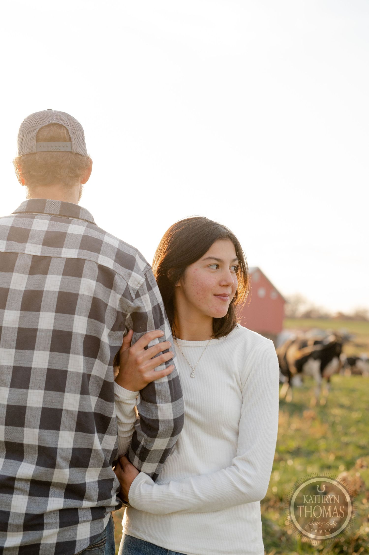 A tender moment captured between a couple on their farm during sunset with a barn in the distance.