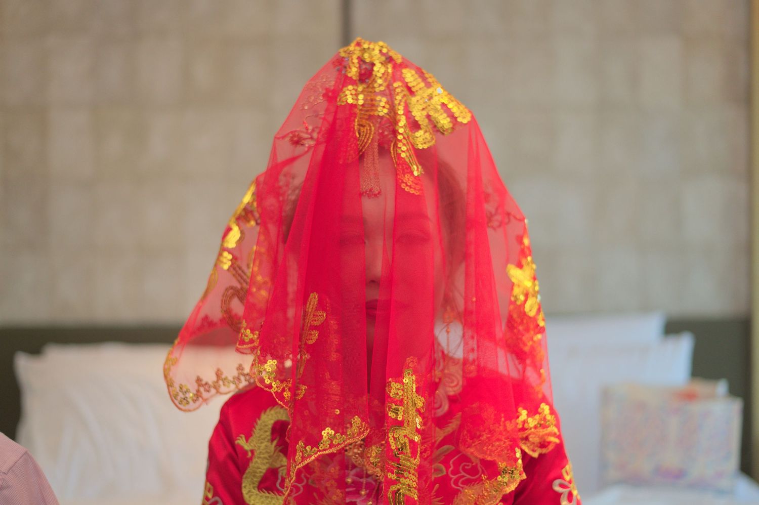 Traditional red and gold embroidered wedding veil draped elegantly against a neutral background.