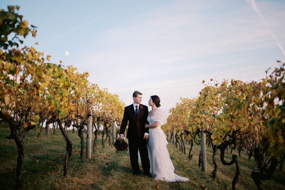 A couple shares a romantic moment in a golden autumn vineyard during sunset.