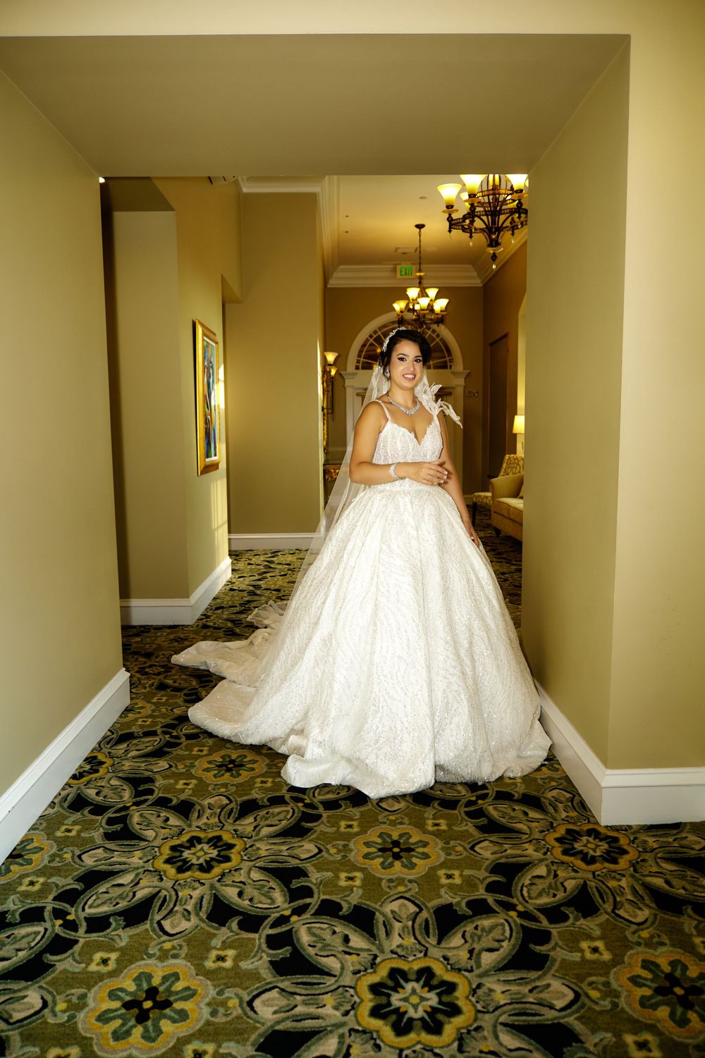 A stunning bridal portrait in a hallway featuring an ornate ball gown and elegant interior design.