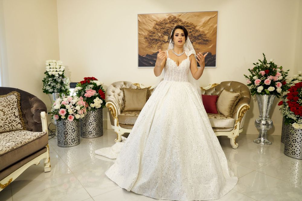 A stunning ball gown wedding dress with sparkly details fills a luxurious room with elegant floral arrangements.