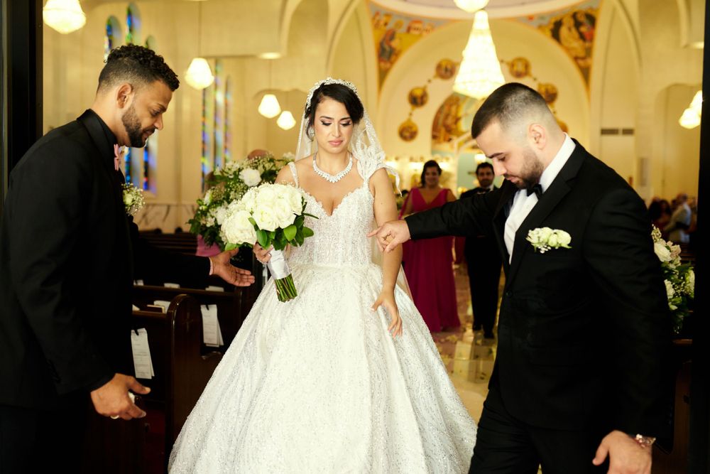 An elegant wedding ceremony scene with white floral decorations in a beautifully lit church interior.