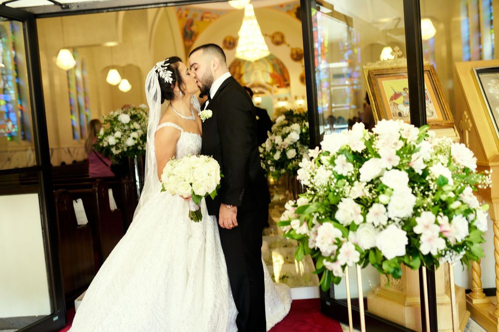 A romantic wedding moment captured in an elegantly decorated venue with white floral arrangements.