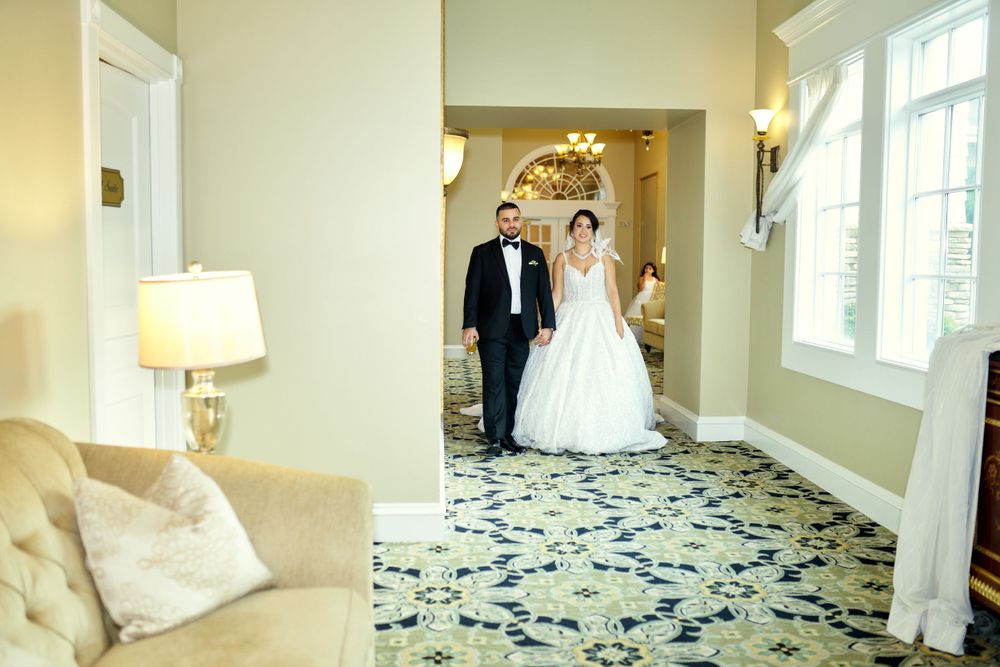 An elegant wedding portrait in a luxurious hallway with patterned carpet and classic decor.