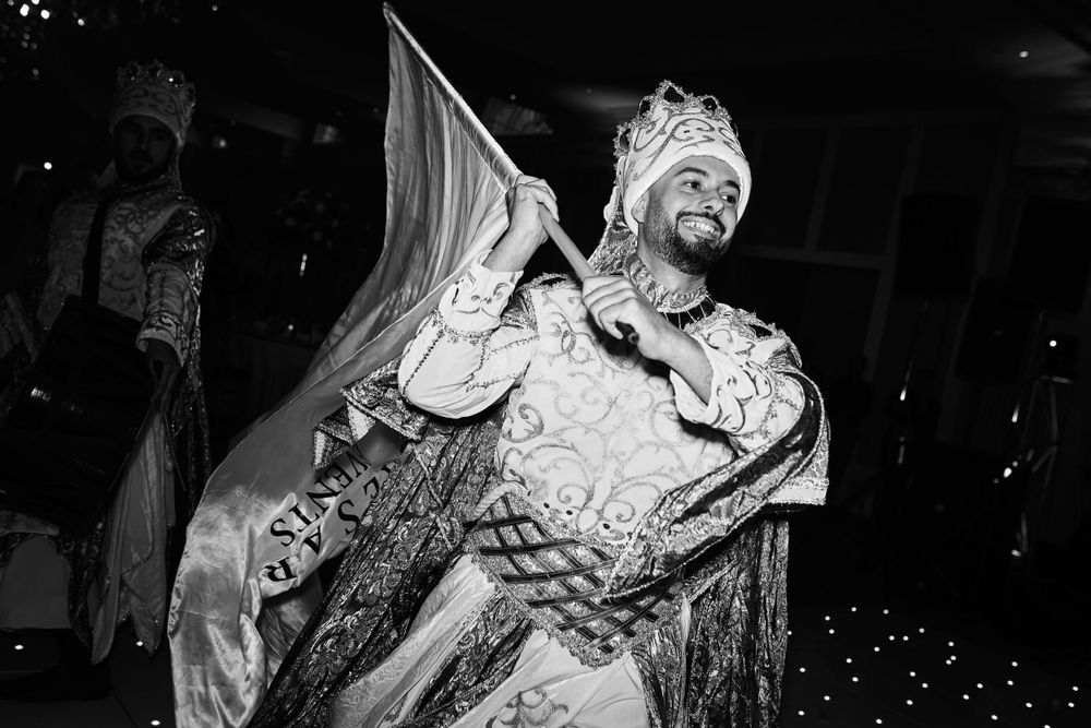 A dramatic black and white portrait of someone wearing elaborate ceremonial or costume attire.