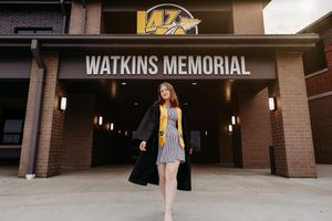 A large brick building entrance with illuminated signage reading Watkins Memorial and multiple glass doors.