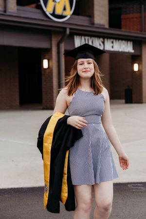A graduate in a striped dress and academic regalia poses outdoors in a series of photos.
