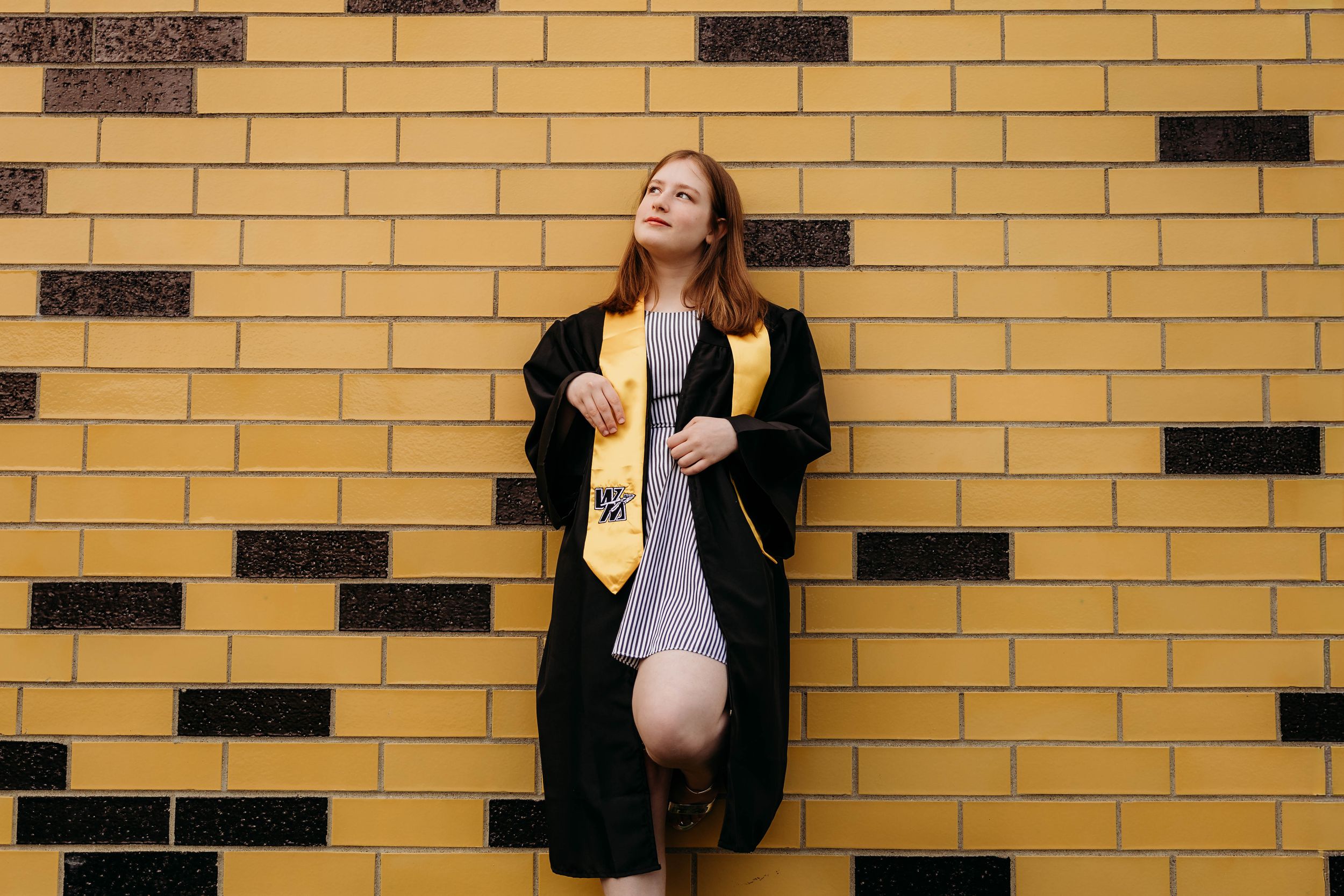 A dancer strikes elegant poses against a yellow brick wall with dark accents.