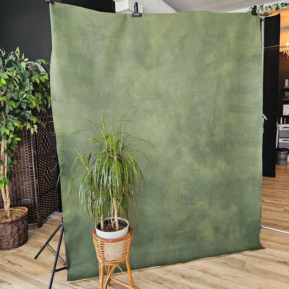 A green textured wall backdrop shown from multiple angles with a potted plant and rattan chair visible in some shots.