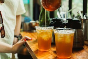 Glasses of craft beer and cocktails lined up on a wooden bar counter in warm lighting.
