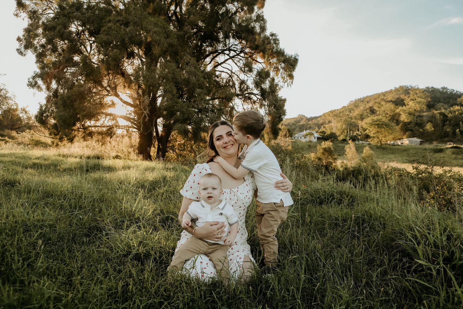 A parent and child share tender moments together in a golden-lit field during sunset.