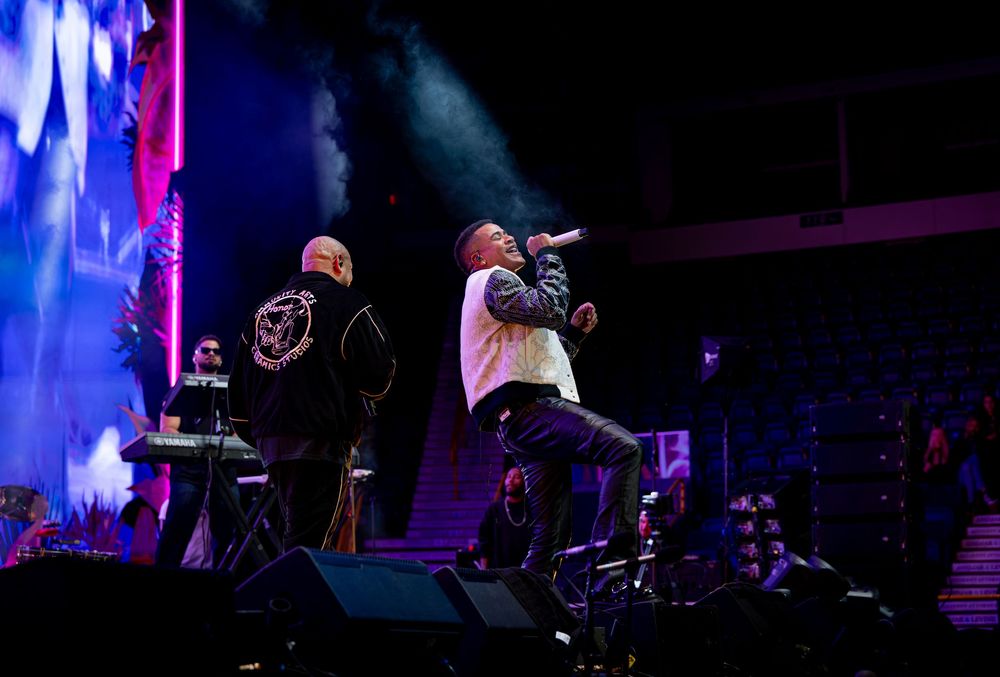 Two male hip-hop artists perform together under blue and pink stage lighting at a live concert.