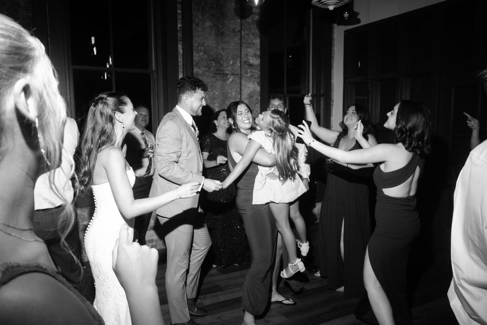 Black and white photo of people dancing together at a party in a dimly lit venue.