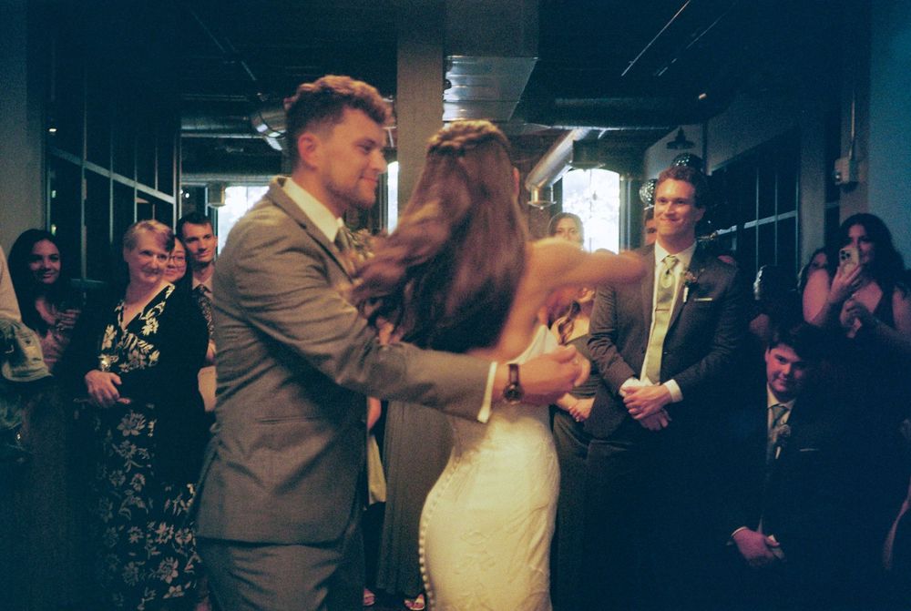 Wedding couple dancing together in formal attire surrounded by guests at an evening reception celebration.