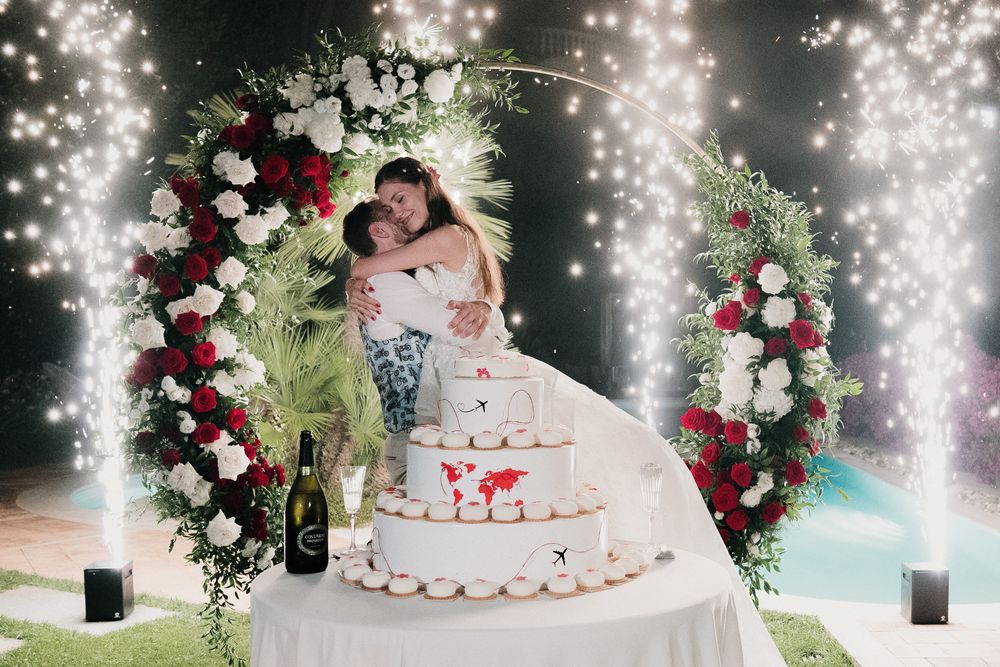 A romantic embrace between the newlyweds in front of the sparkling wedding cake at Villa Casa Rossa in Imperia.