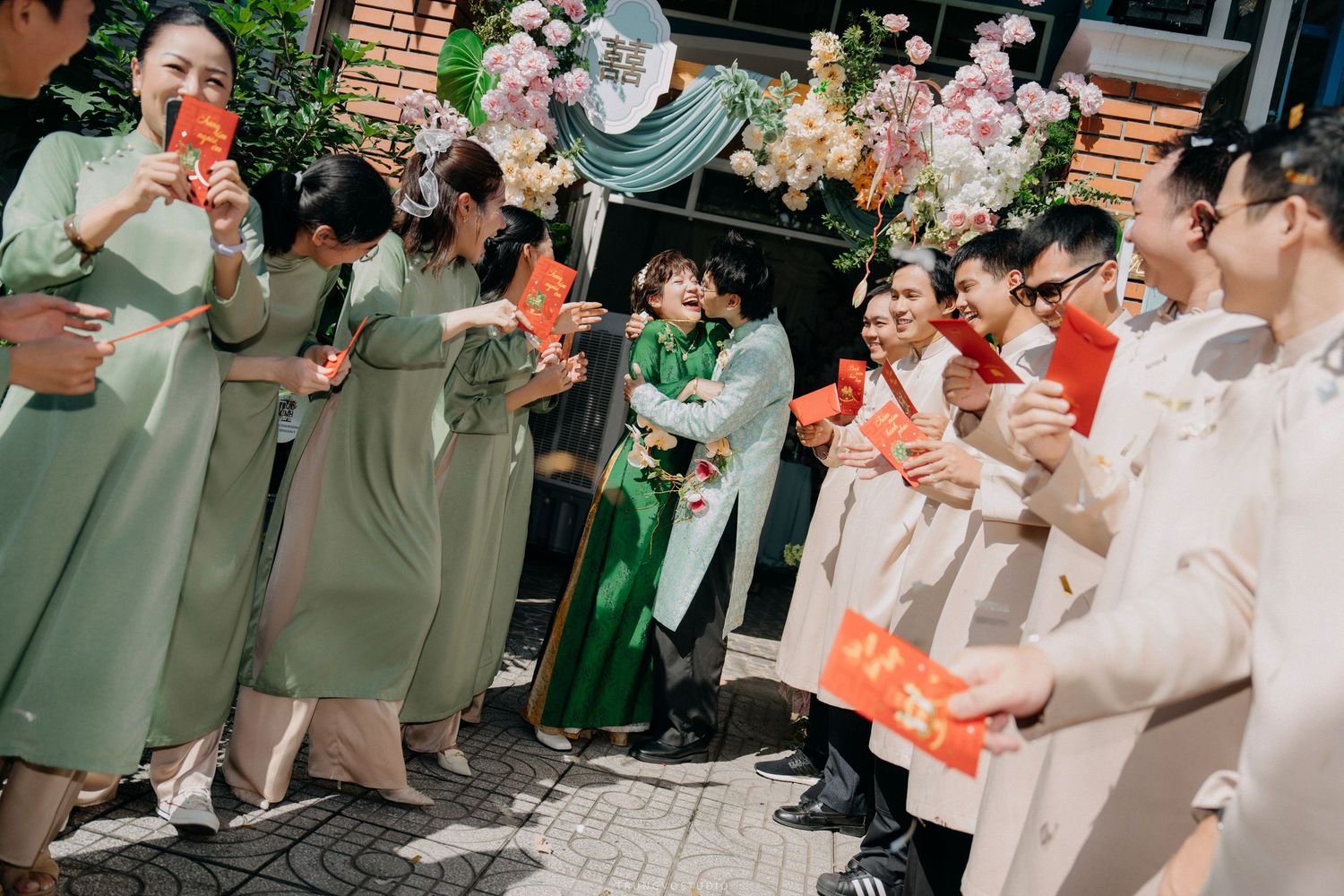 Wedding party in traditional Vietnamese ao dai attire celebrating outside a decorated venue entrance.