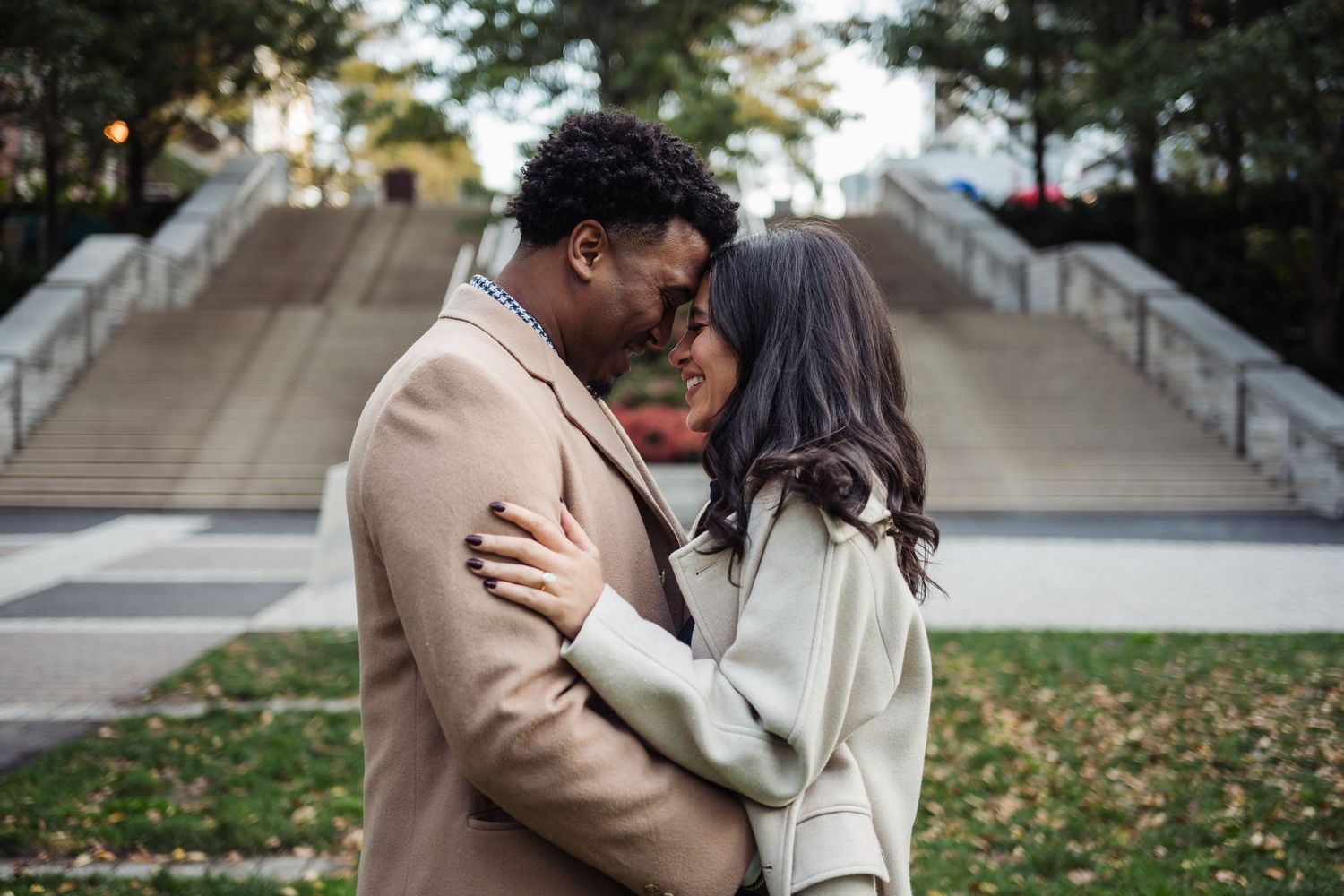 A romantic couple shares an intimate moment on a park bench surrounded by autumn leaves.