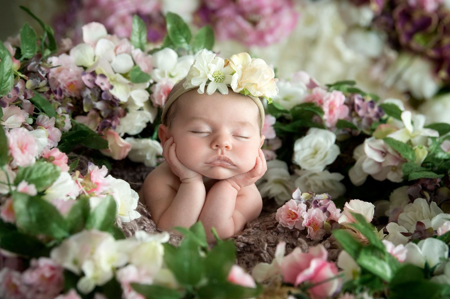 Sleeping baby nestled among delicate pink and white spring blossoms in a dreamy garden setting.