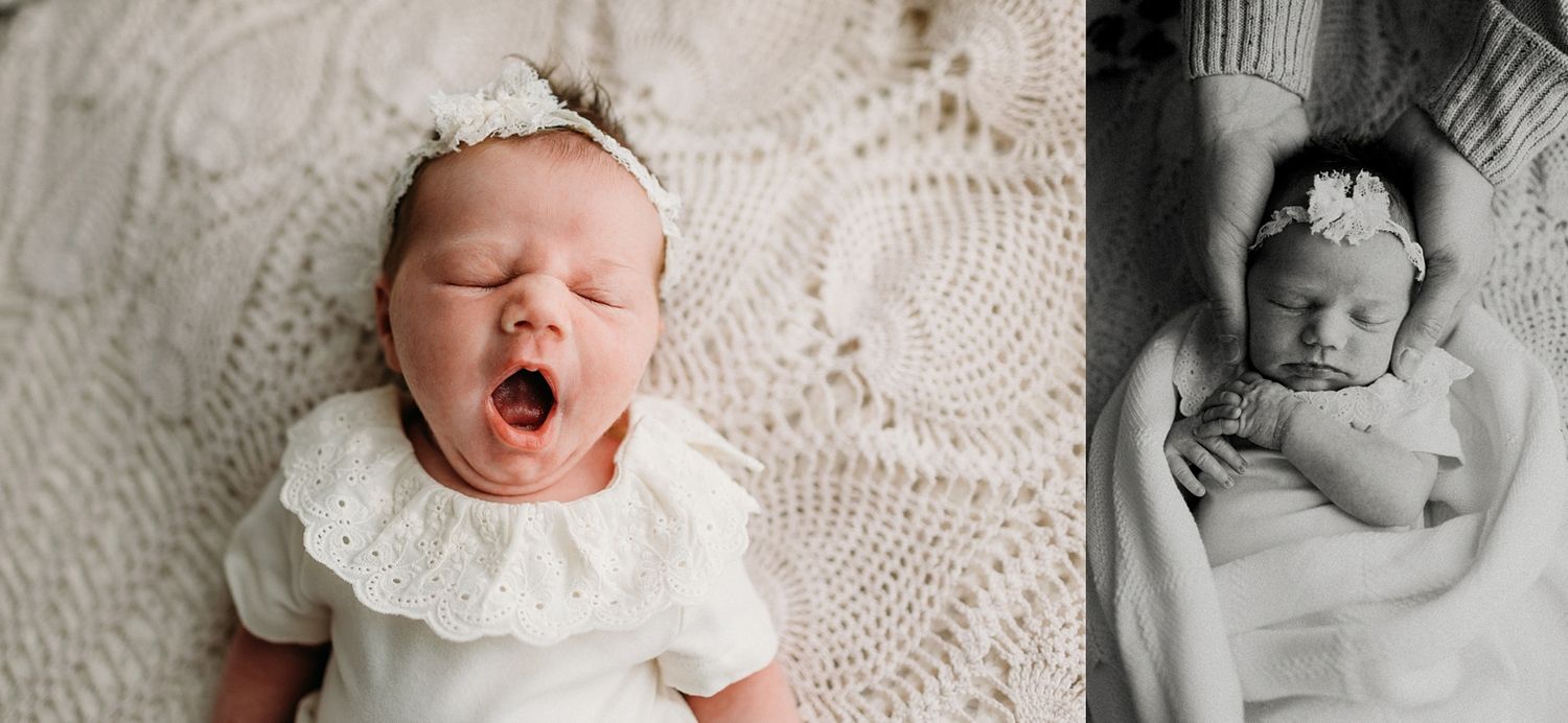 A newborn baby yawns while lying on white lace fabric next to a black and white portrait.