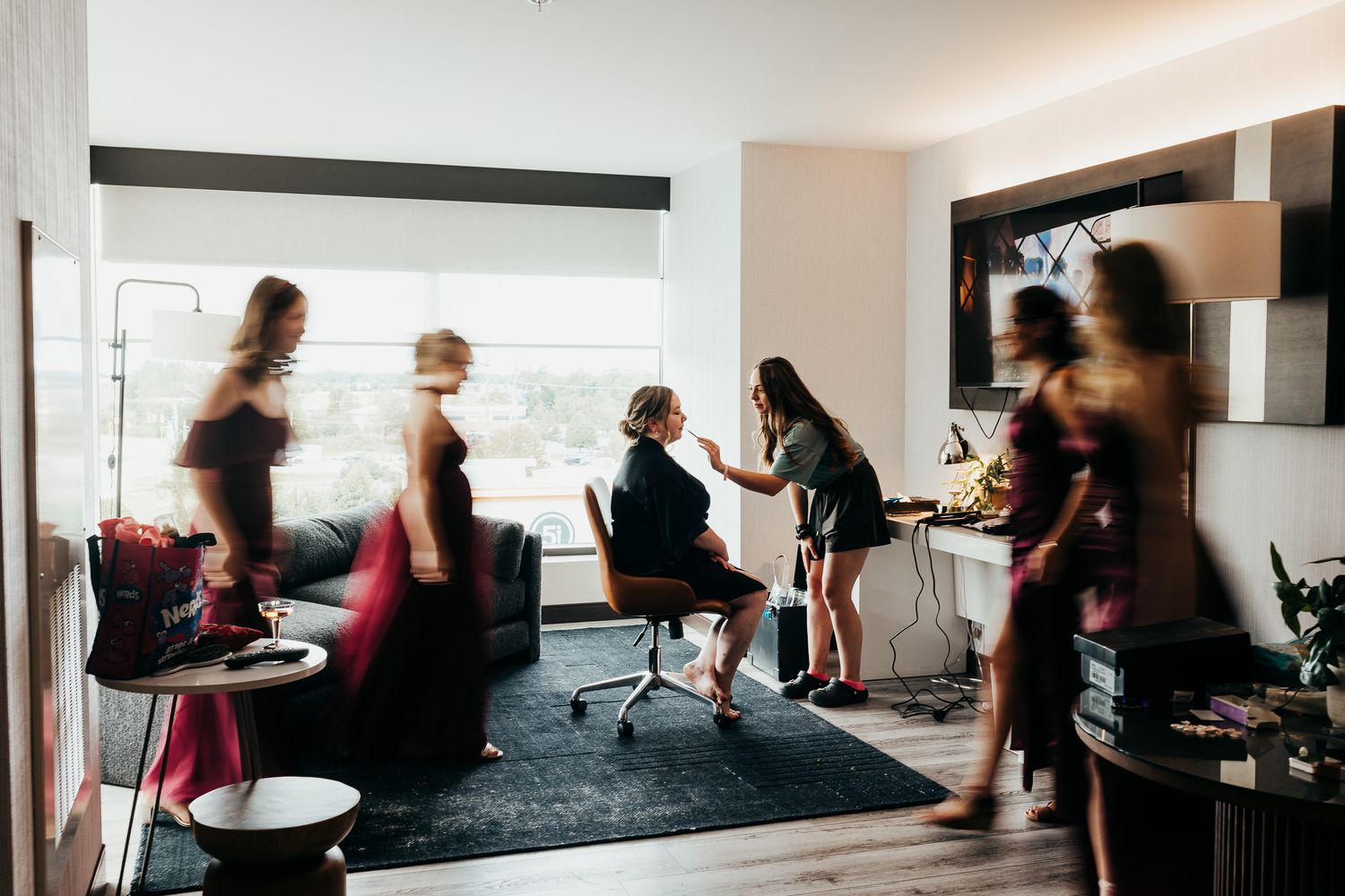 Students participate in a drum circle workshop in a modern studio space with black carpet and white walls.