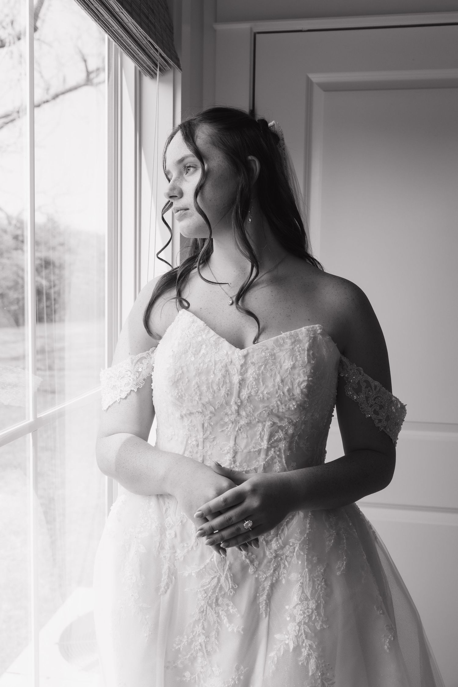 Elegant white lace wedding dress details captured in soft window light.