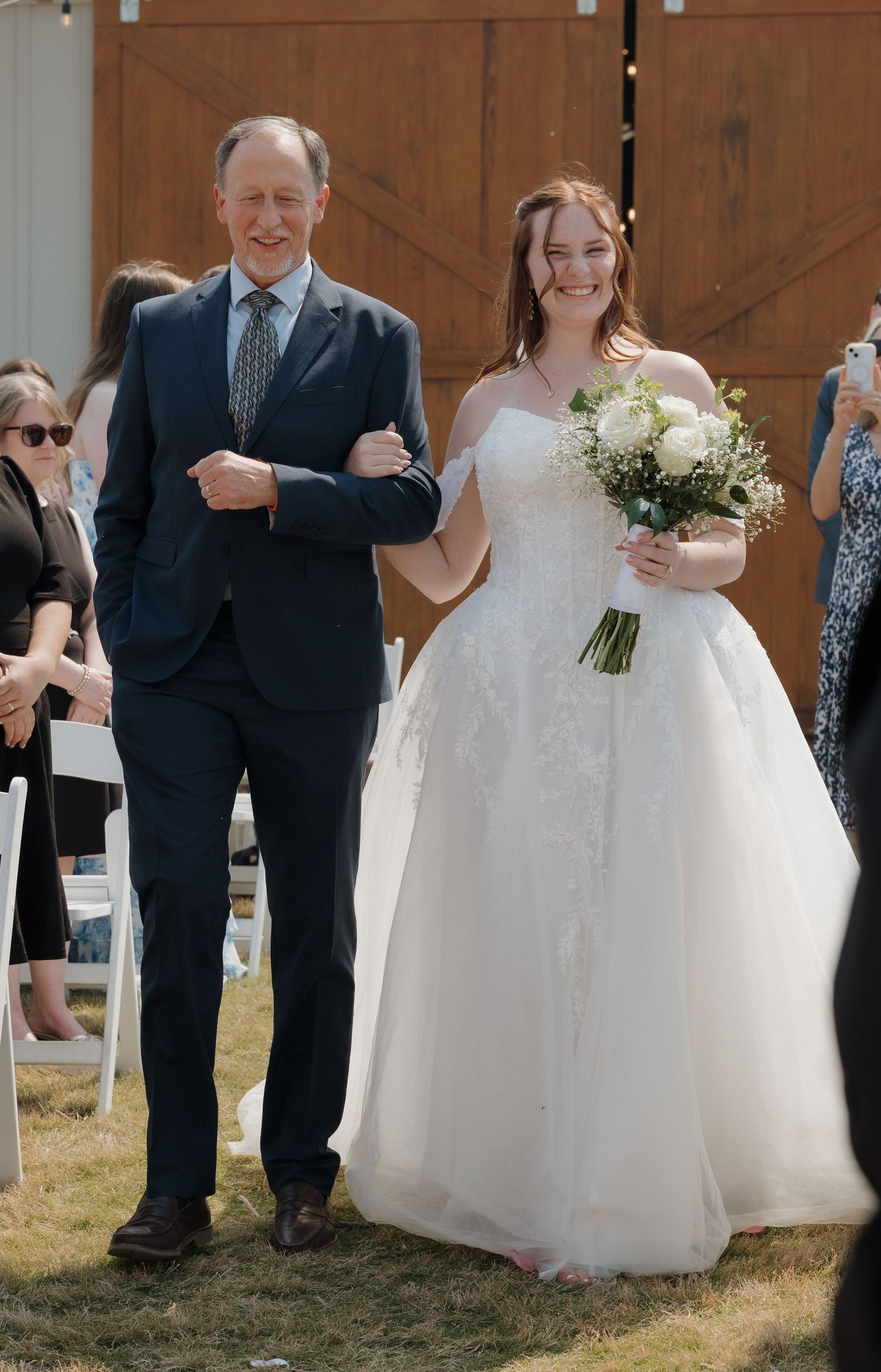 Wedding party in formal attire walking outdoors during ceremony.