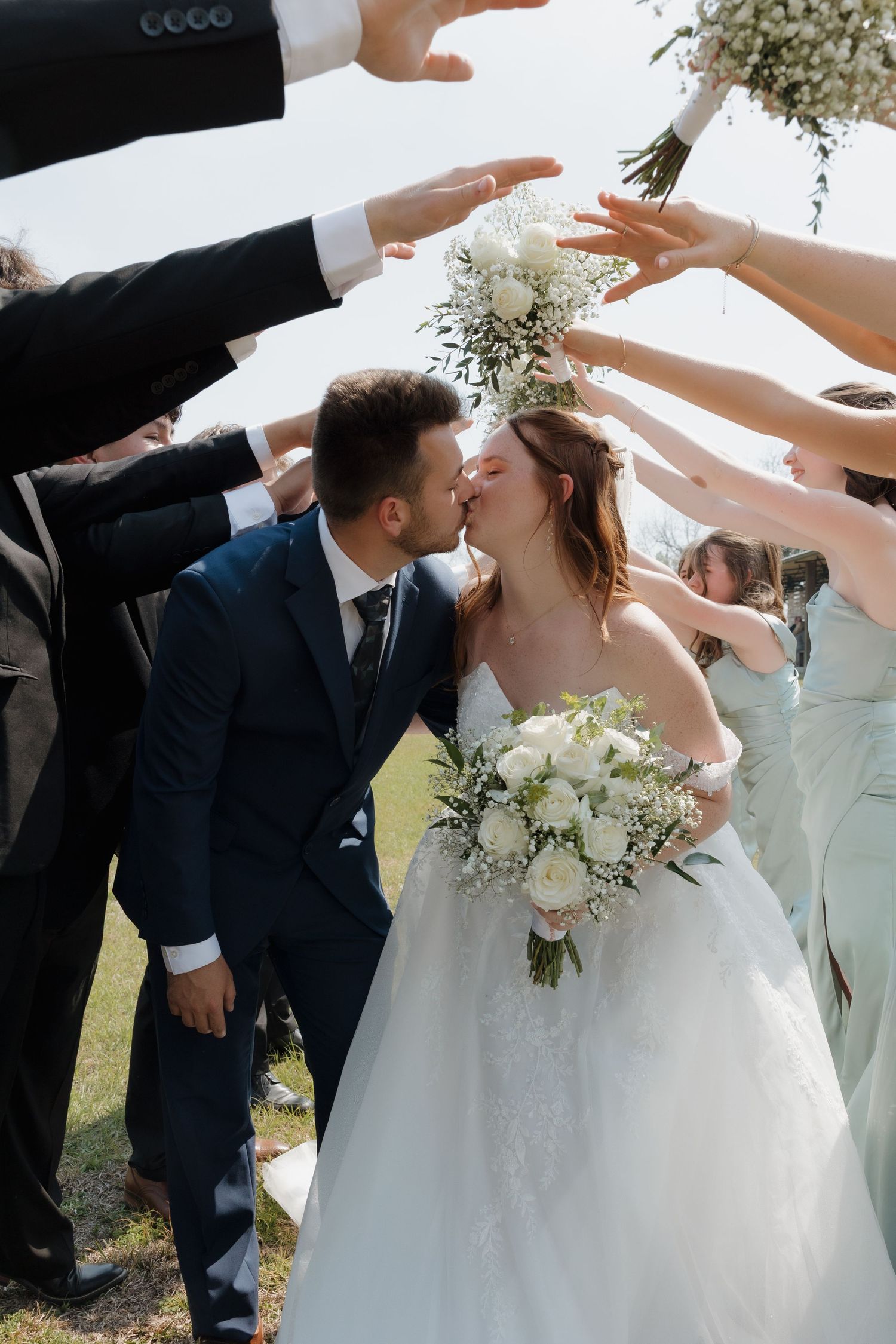 Wedding guests shower the newlyweds with flower petals during an outdoor celebration.