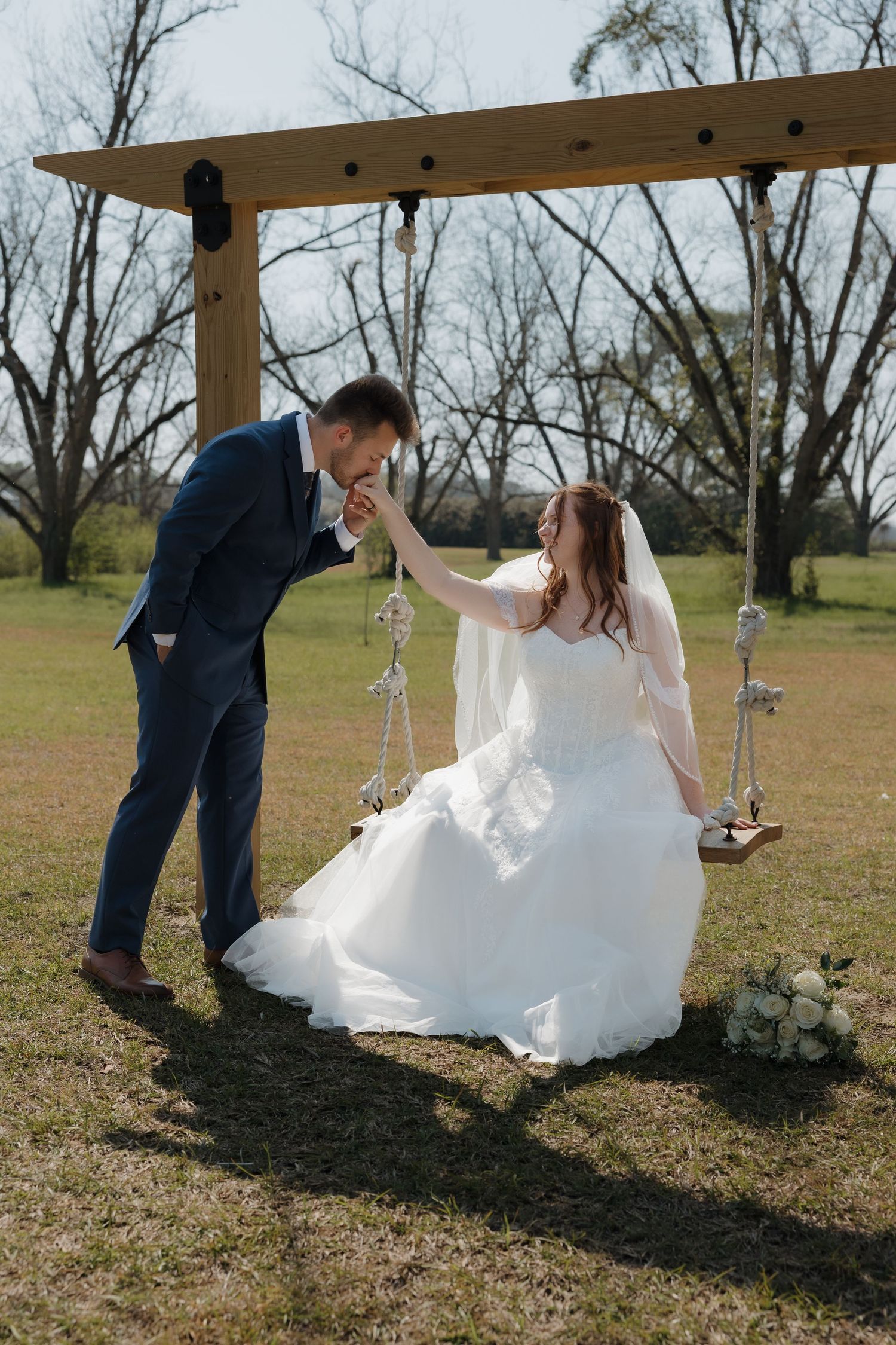 Couple playfully poses for photos in an outdoor setting with hanging decorations.