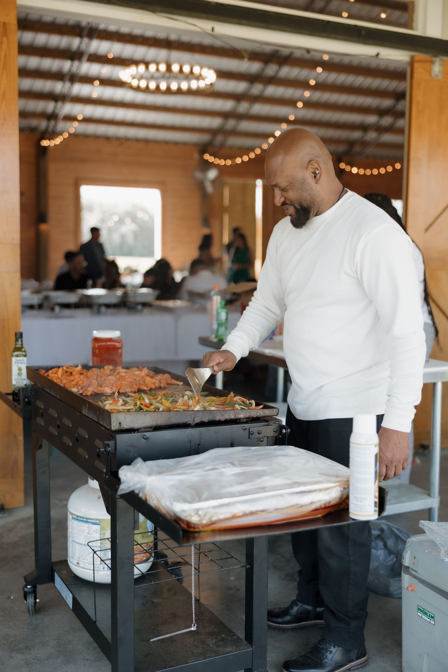 Catering staff preparing food at serving stations in a rustic venue.