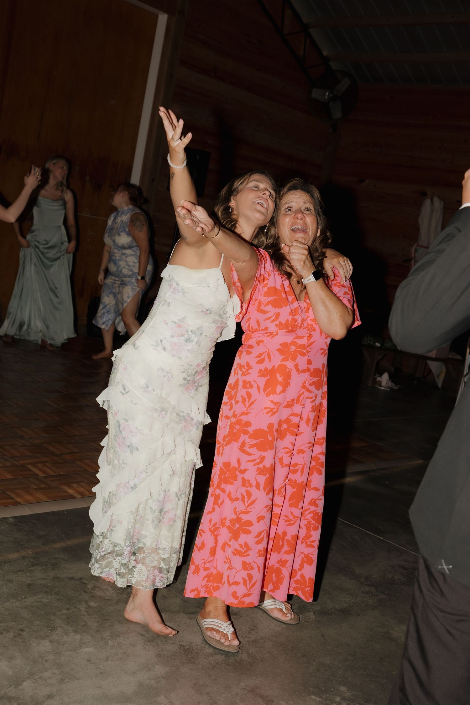 Wedding guests dancing energetically on the dance floor in colorful dresses.