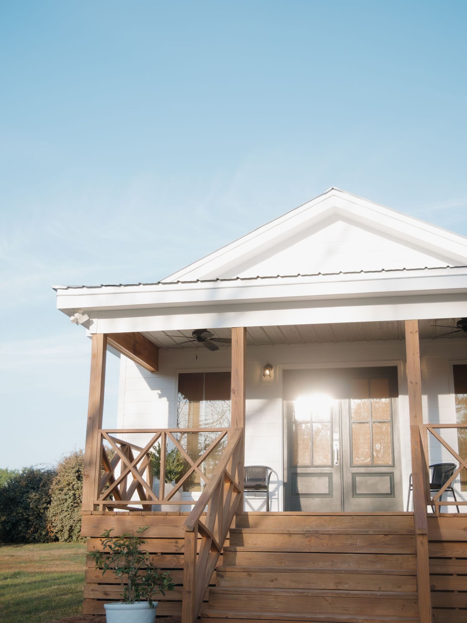 A white coastal-style house with a wraparound porch and wooden deck shown from different angles.