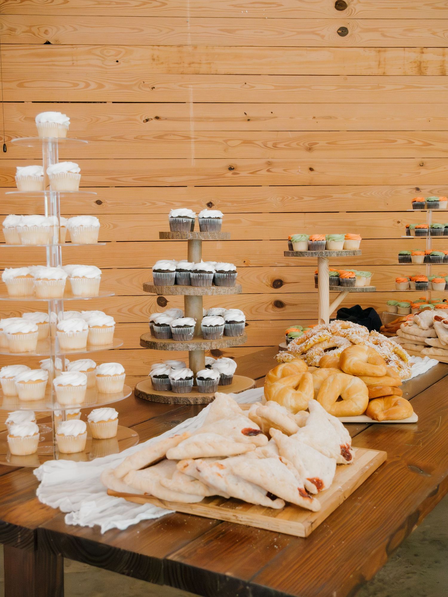 Wedding reception dessert table with donuts and treats displayed on wooden surfaces.