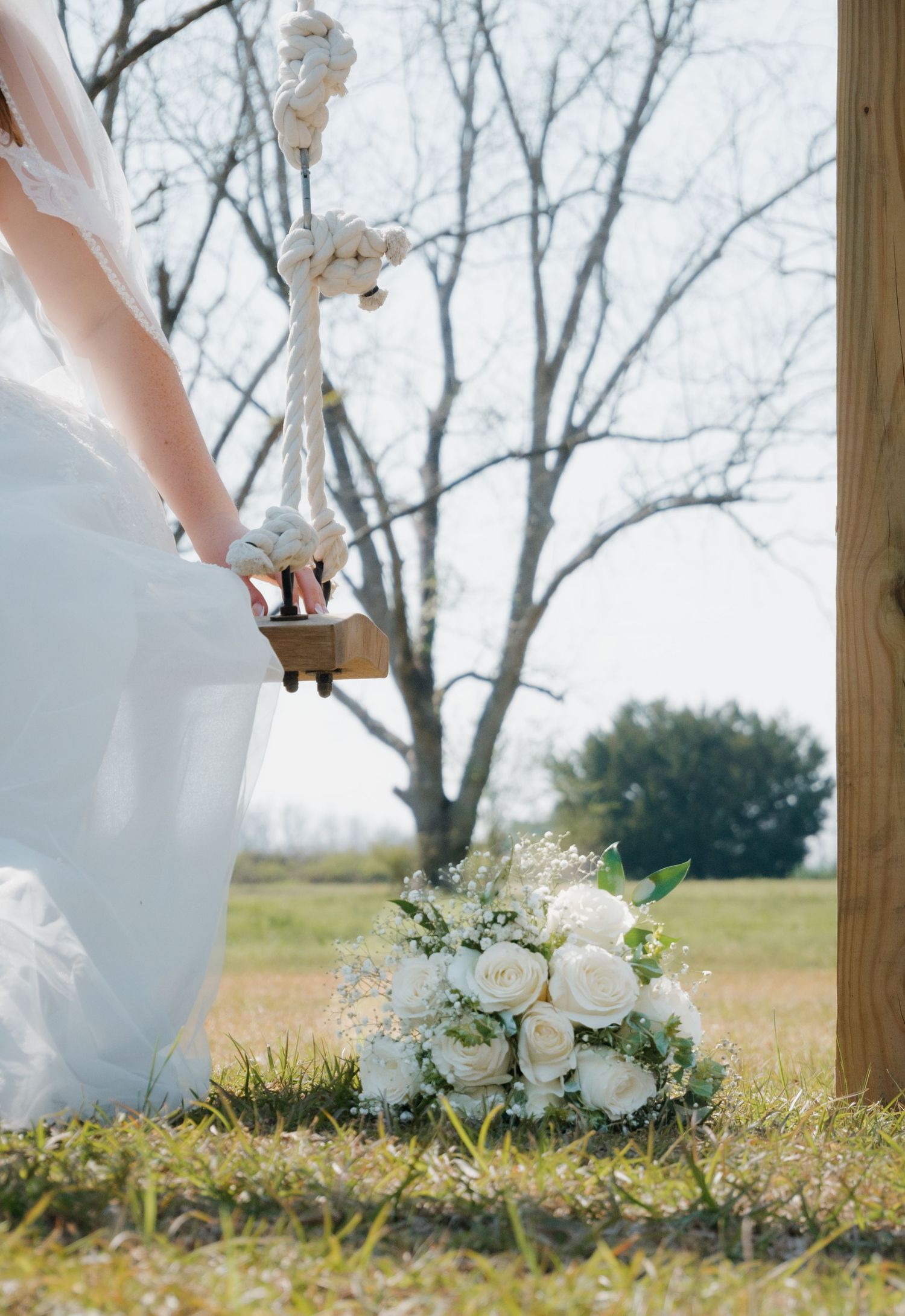 Close-up of white wedding dress and bouquet against natural outdoor backdrop.