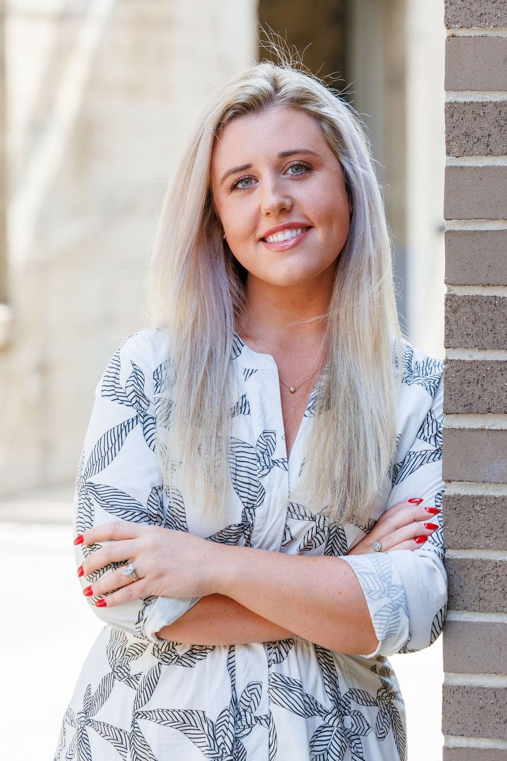 A person in a white and black patterned top poses against a brick wall in a series of casual portraits.