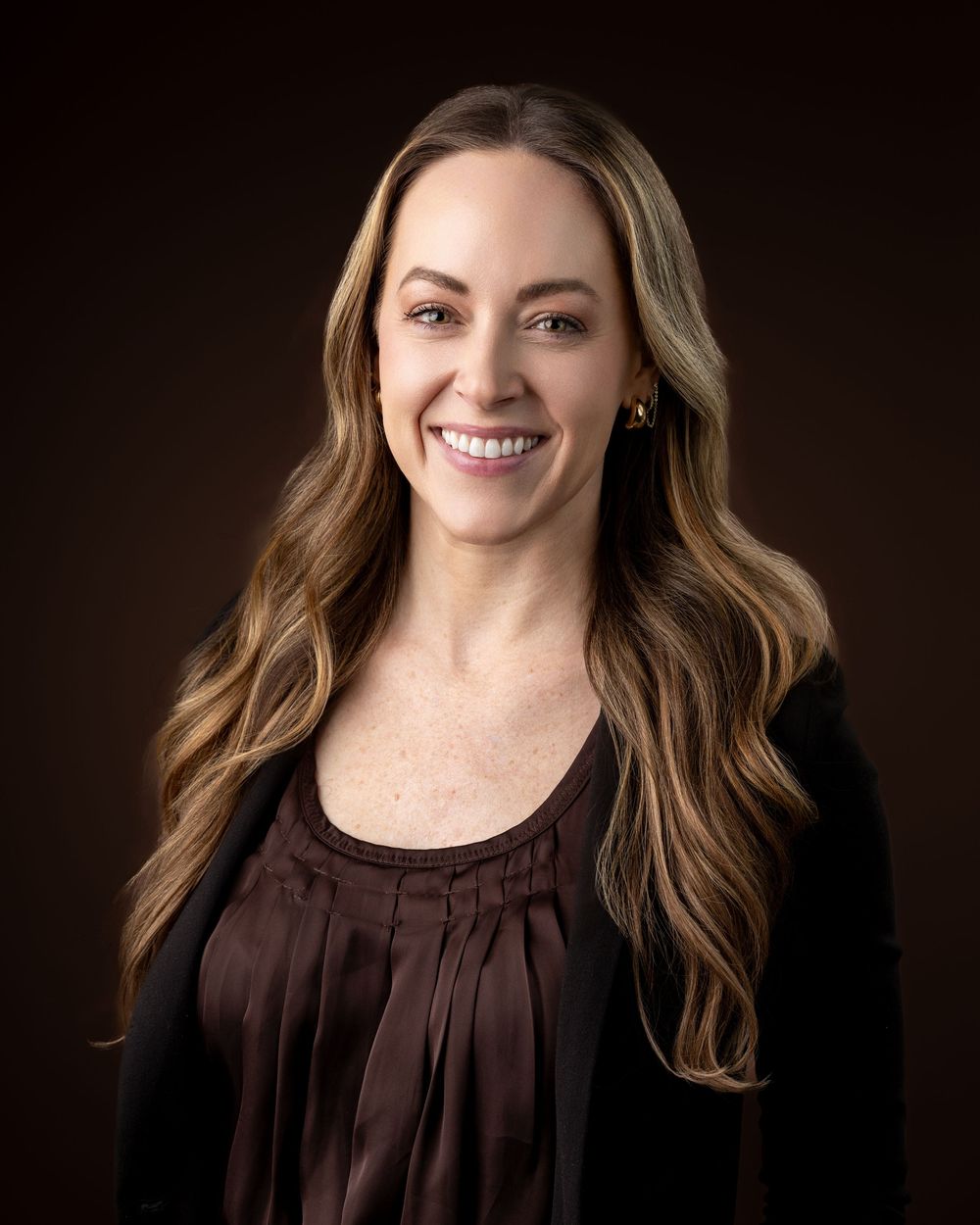 Professional portrait series featuring someone in a dark brown pleated top against a black studio background.