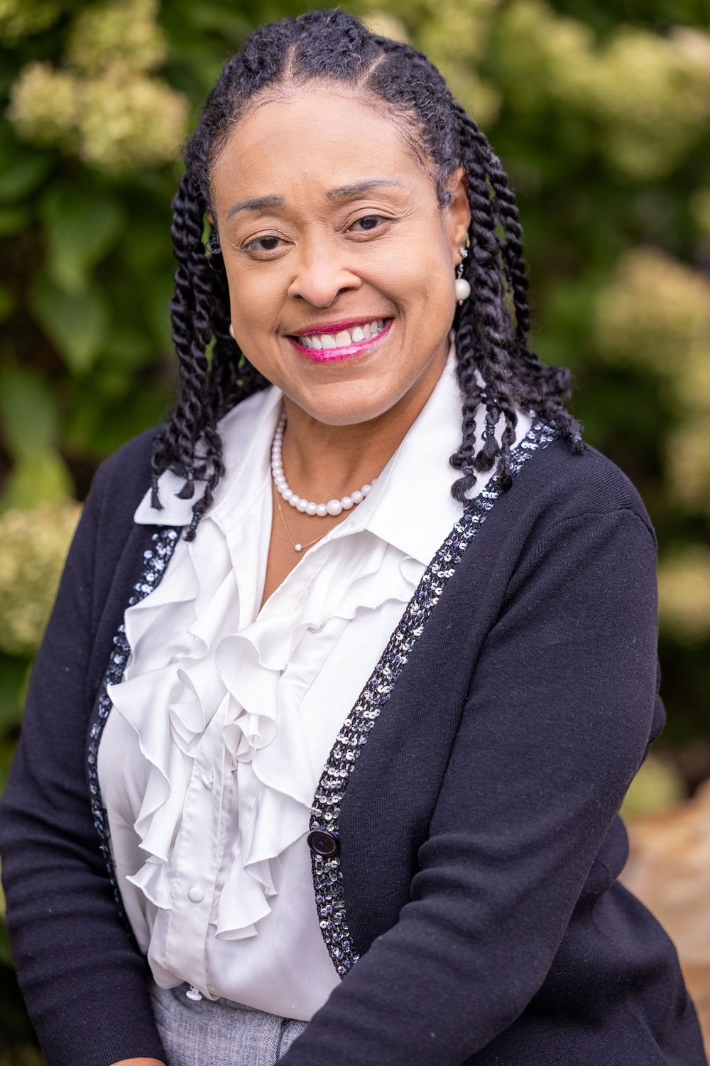 Professional headshots showing a person in a black cardigan and white ruffled blouse against a natural outdoor background.