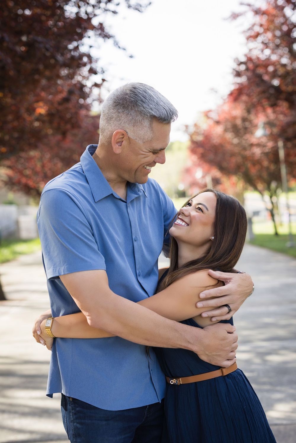 Couple sharing affectionate moments outdoors with autumn trees in background.