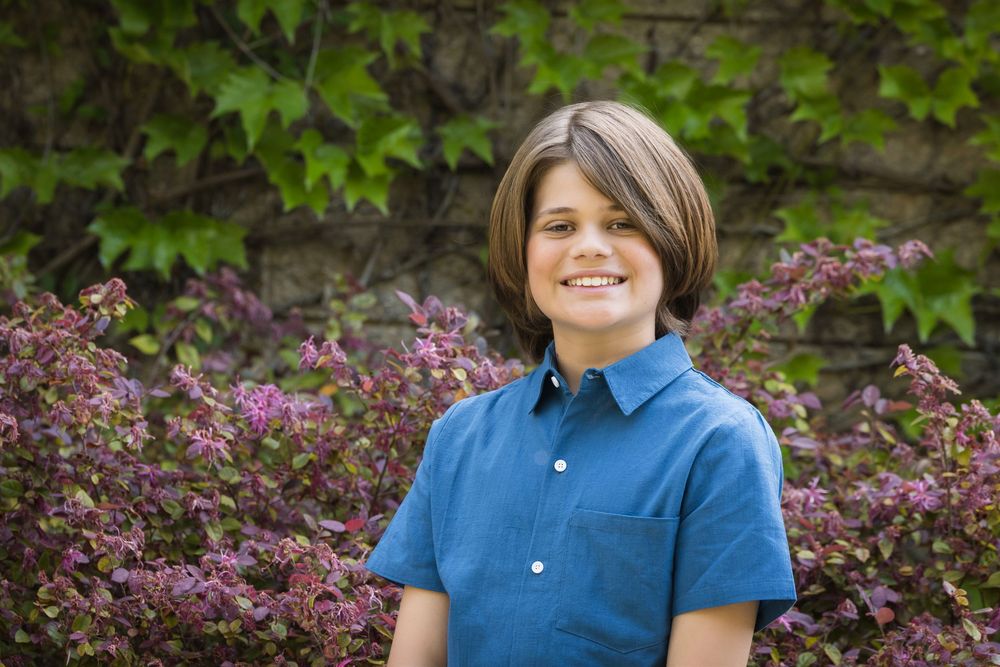 Outdoor portrait session in front of lush green foliage and purple flowering bushes.