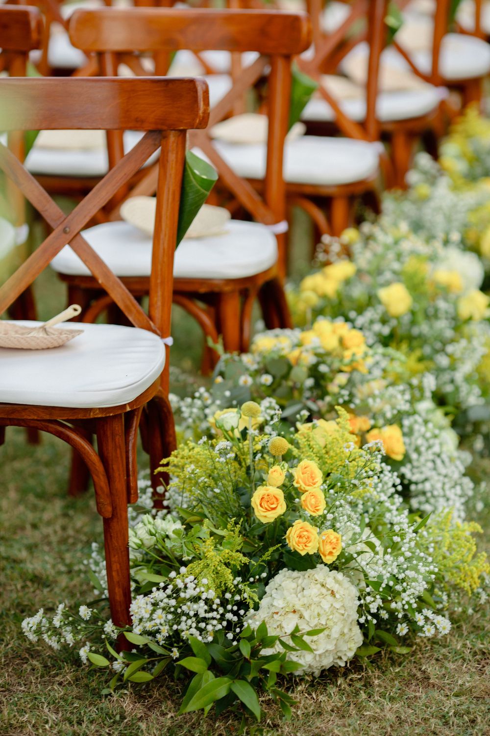 Wooden wedding chairs lined along a flower-filled aisle set for an outdoor Koh Samui ceremony.