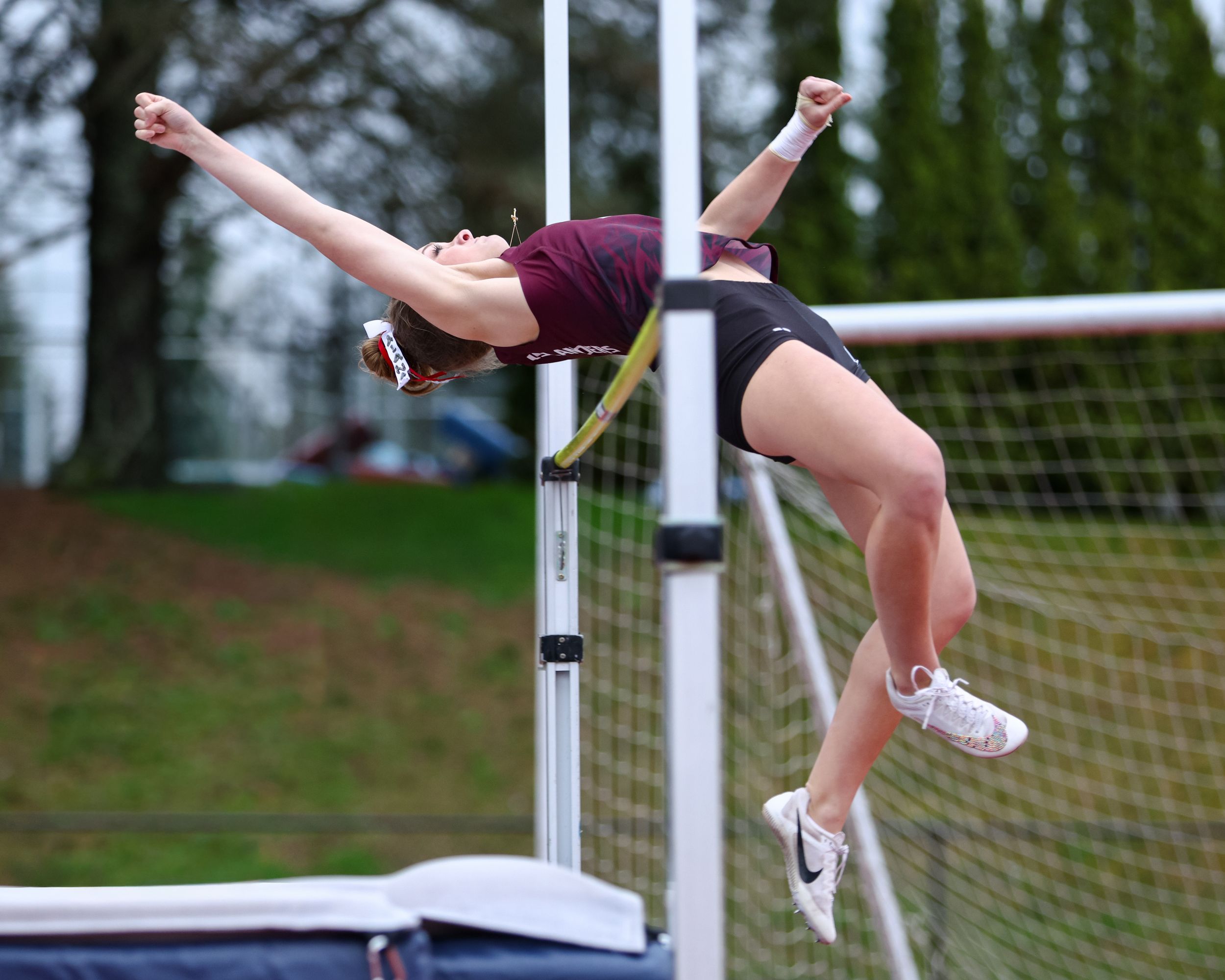 Female athlete performing a high jump using the Fosbury Flop technique at an outdoor track and field competition.
