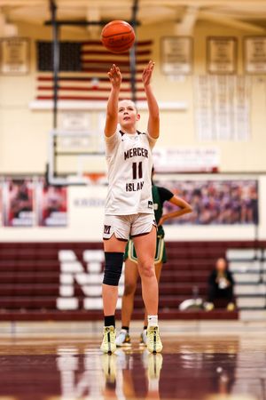 Mercer Island #11 basketball player shoots a free throw during an indoor high school girls basketball game.