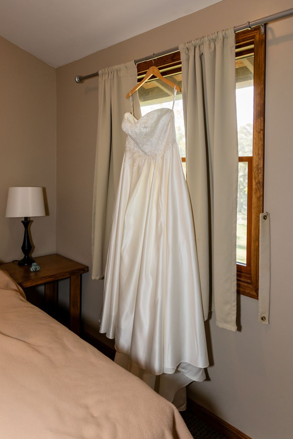 Elegant strapless white wedding gown in a cozy bedroom  at the Cottonwood Lodge in Platte River State Park in Louisville