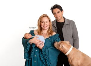 A group of people and a dog pose together for a casual photoshoot against a white background.