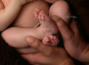 Close-up of a newborn baby's tiny feet cradled gently in adult hands, showcasing delicate details.