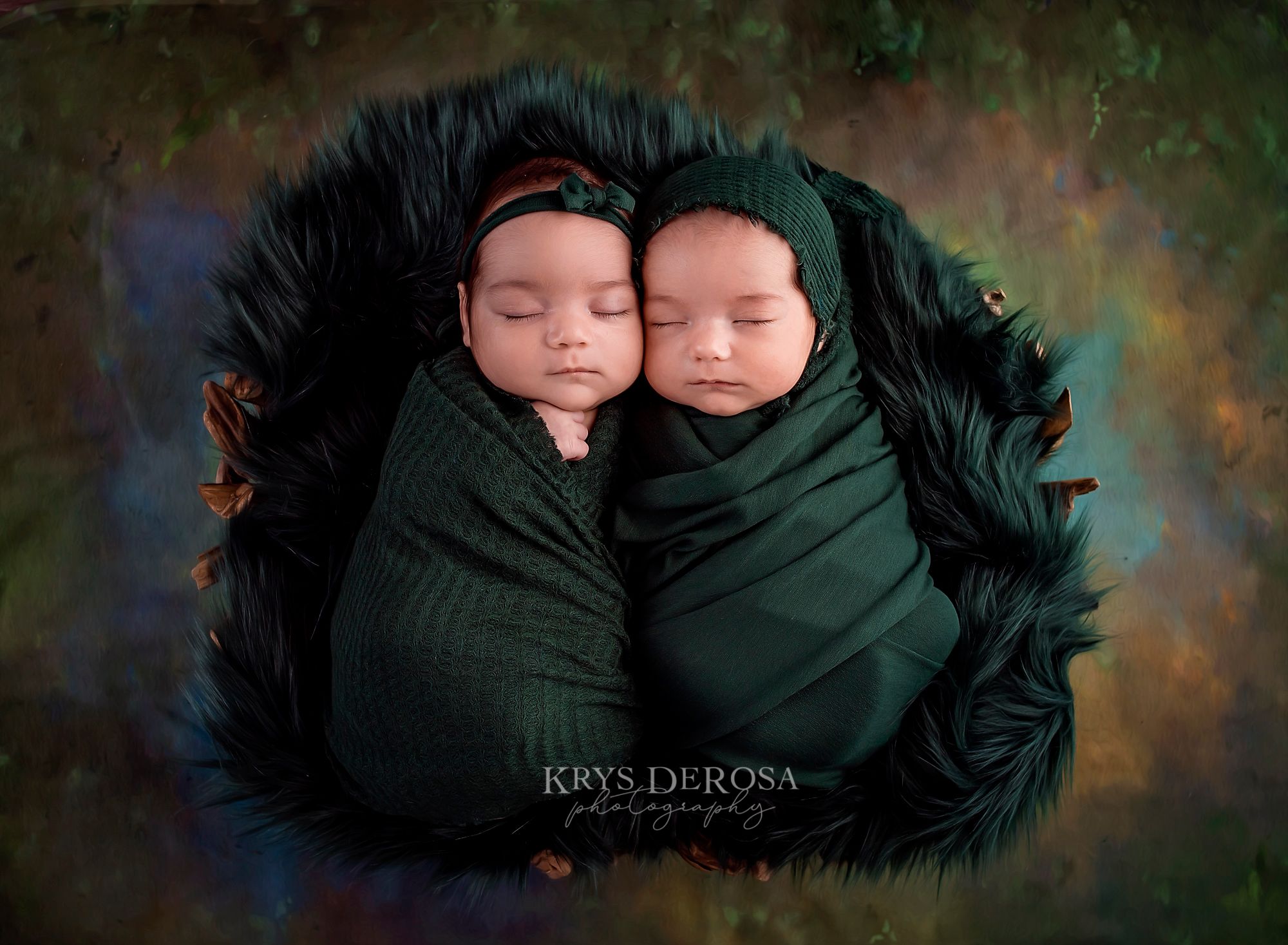 Twin newborns swaddled in matching green wraps, sleeping side by side in a dark fur bowl on colorful background.