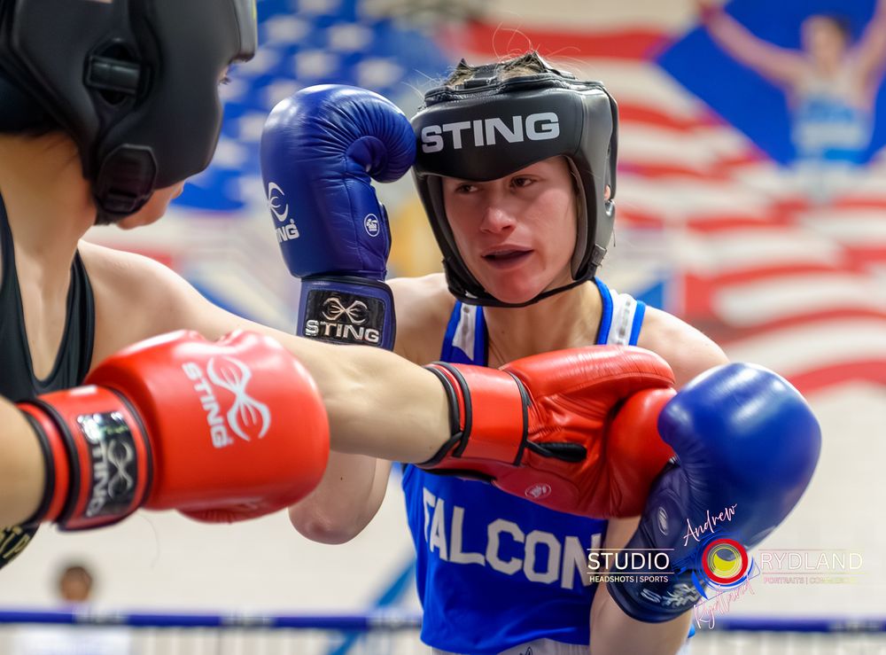 Boxing match with two fighters in red and blue gear exchanging punches in the ring.