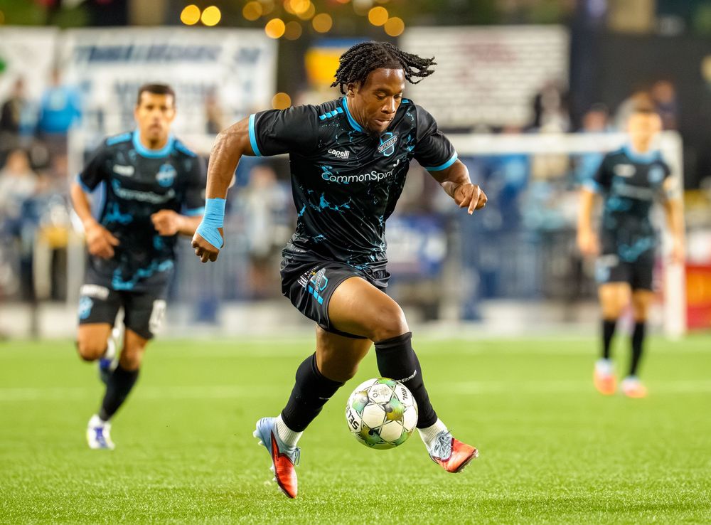 Soccer players sprint across field during intense match under stadium lights.