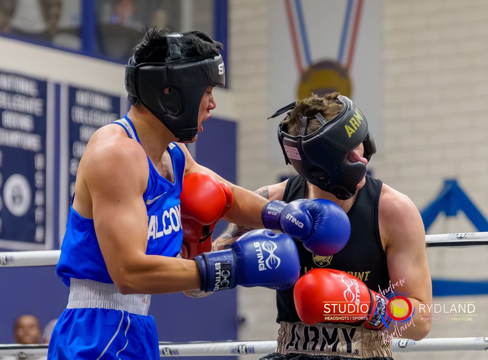 Two boxers spar in a practice ring wearing protective headgear and gloves during training.