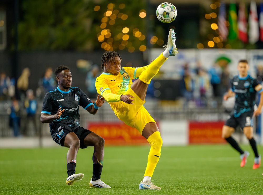 Soccer players compete for control of the ball during an intense match on a grass field.