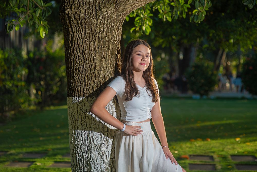 Family photoshoot in Guanacaste, outdoor portraits in a park setting with sunlit trees and grass in the background.